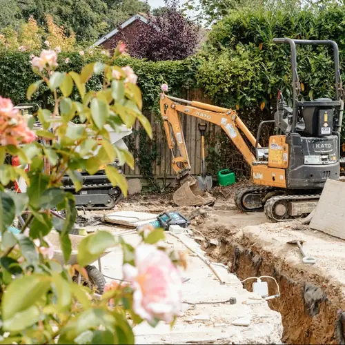 Mini excavator digging a trench in a backyard